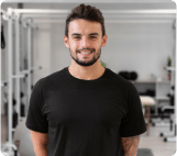 Personal homem de camisa preta sorrindo enquanto está em uma academia