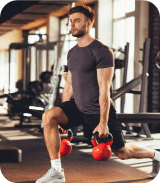 Um homem em uma academia faz lunges enquanto segura dois alteres vermelhos, personificando um estilo de vida saudável