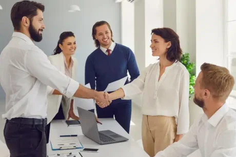 5 pessoas felizes finalizando uma reunião em uma mesa de trabalho para ilustrar um rh menos burocrático